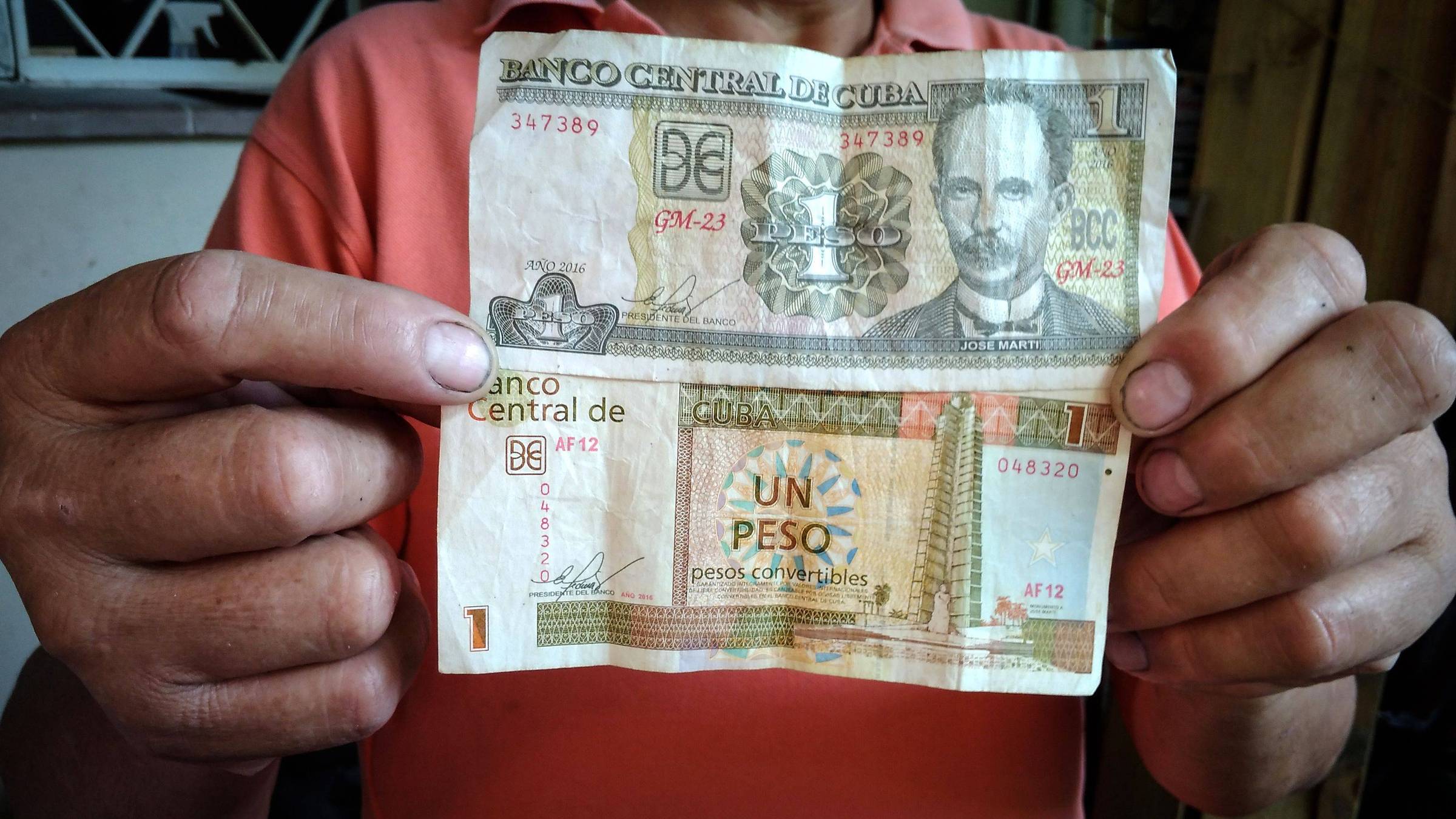 Vendedor em Havana mostra uma nota de peso cubado (cup) e outra de peso conversível (cuc)