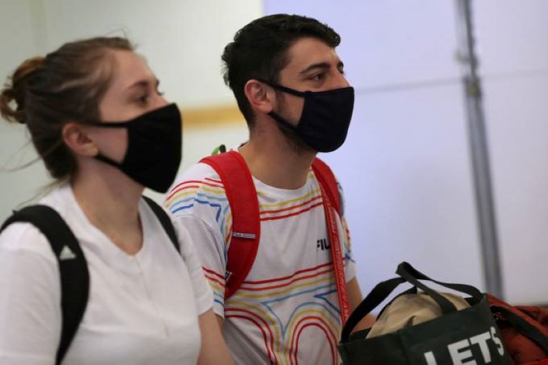 Viajantes, usando máscaras como medida de precaução para evitar a contração de coronavírus
