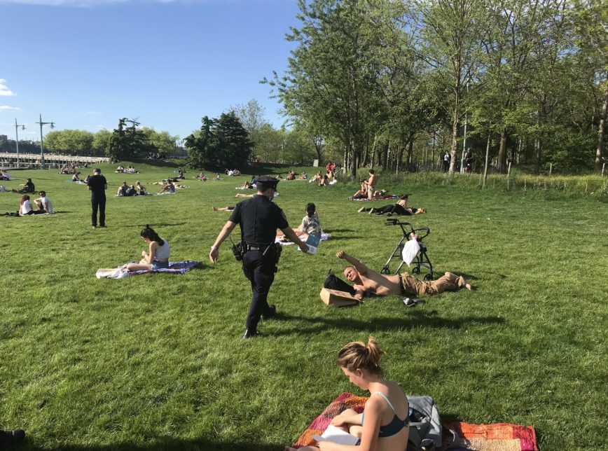 Policial entrega mascara para pessoas no Hudson River Park, em Nova York
