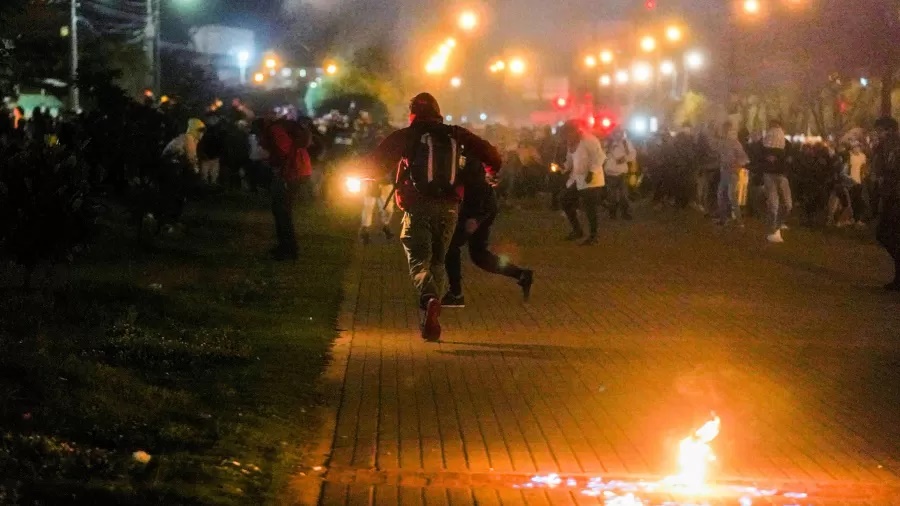 Manifestantes correm enquanto gás lacrimogêneo cai durante um protesto em Bogotá, Colômbia