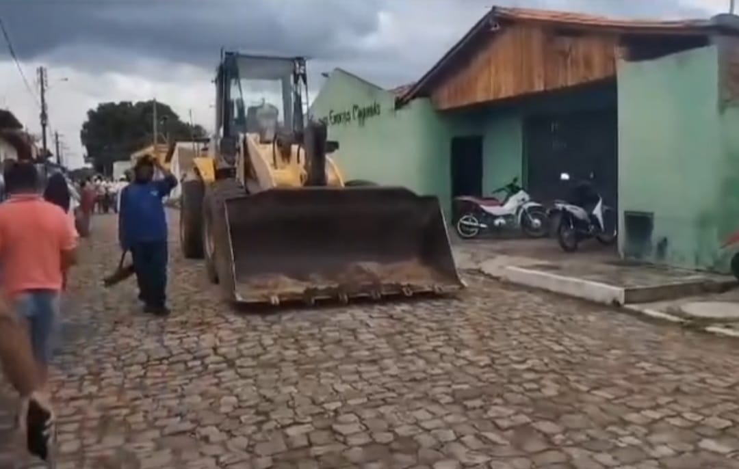 Máquinas da prefeitura posicionadas no meio da rua, bloqueando o acesso à obra